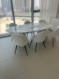 Volakas White Marble oval dining table with chairs in a Dubai apartment with city view